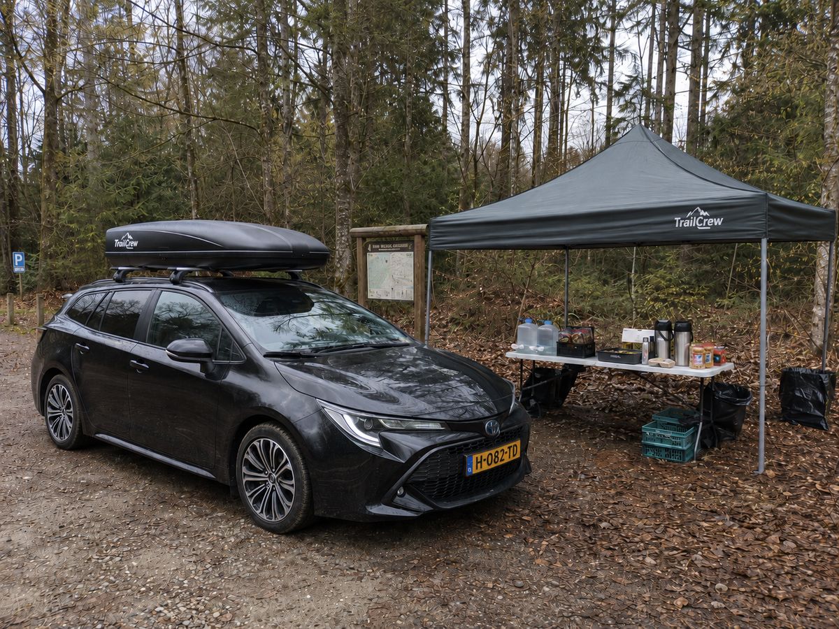 Het TrailCrew-basecamp: auto met dakkoffer en tent in het bos